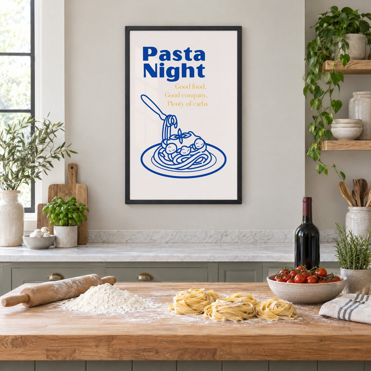 Pasta Night cobalt spaghetti and meatballs print in a black frame above a butcher-block island with fresh pasta, flour and cherry tomatoes