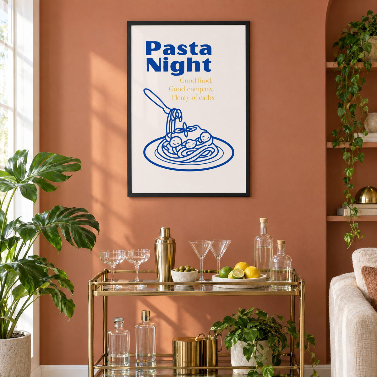 Pasta Night cobalt spaghetti and meatballs print in a black frame on a terracotta wall above a brass bar cart with coupes and citrus