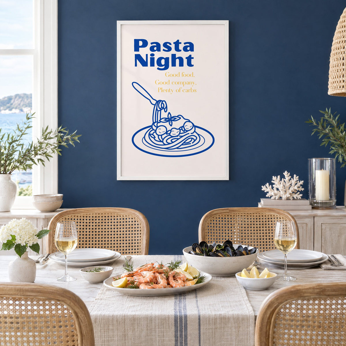 Pasta Night cobalt spaghetti and meatballs print in a white frame on a navy wall above a dining table set with shrimp and mussels