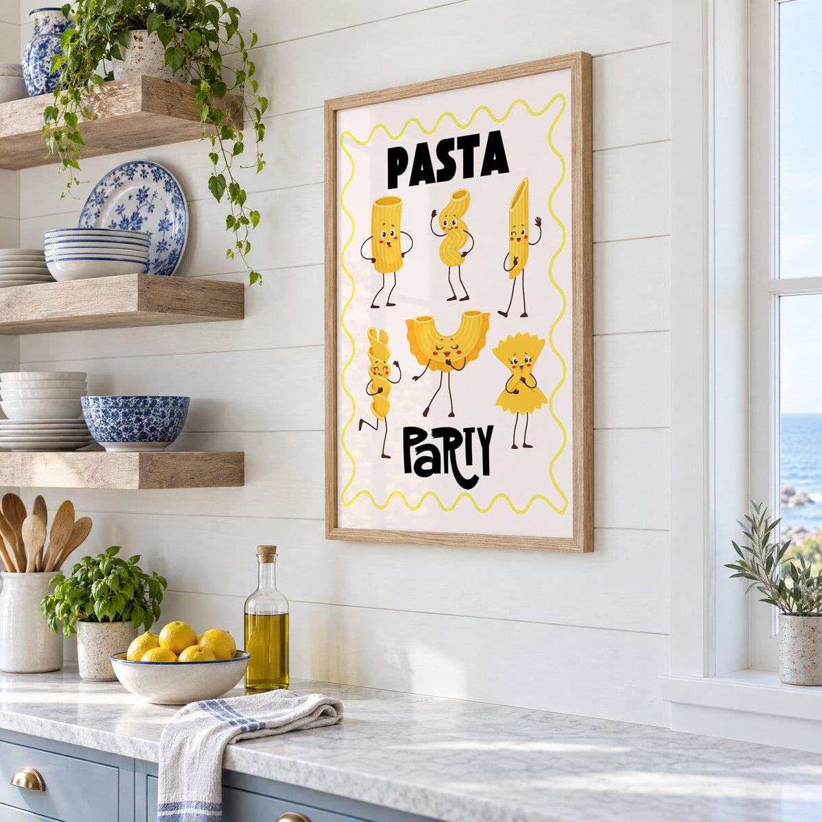 Pasta Party cartoon noodles print in an oak frame in a white coastal kitchen beside blue and white plates