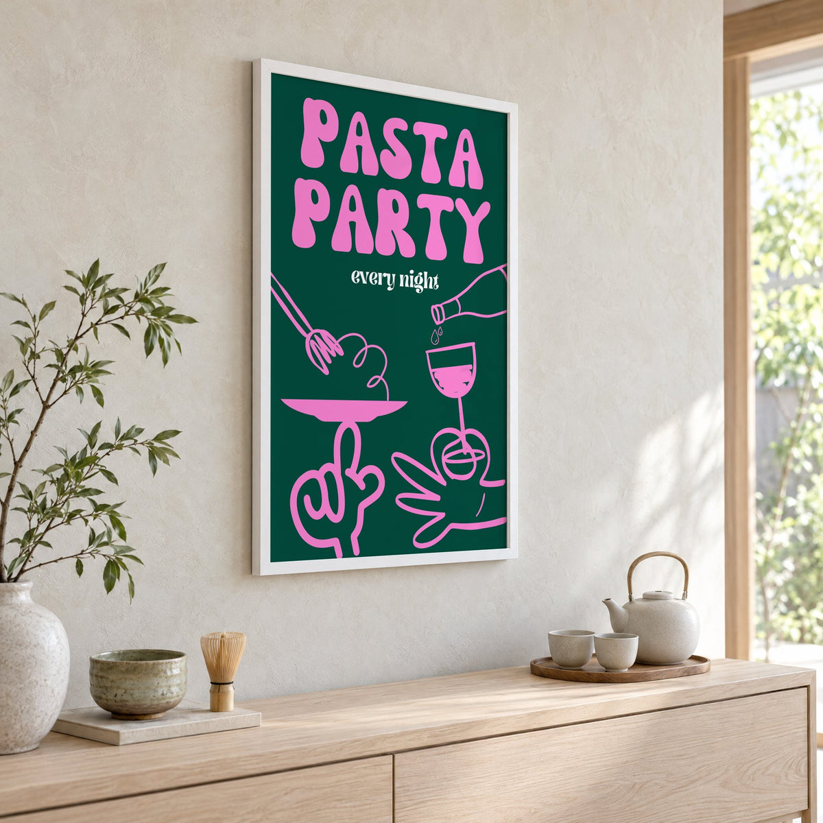 Pasta Party every night green print in a white frame above a pale wood console with a matcha tea set