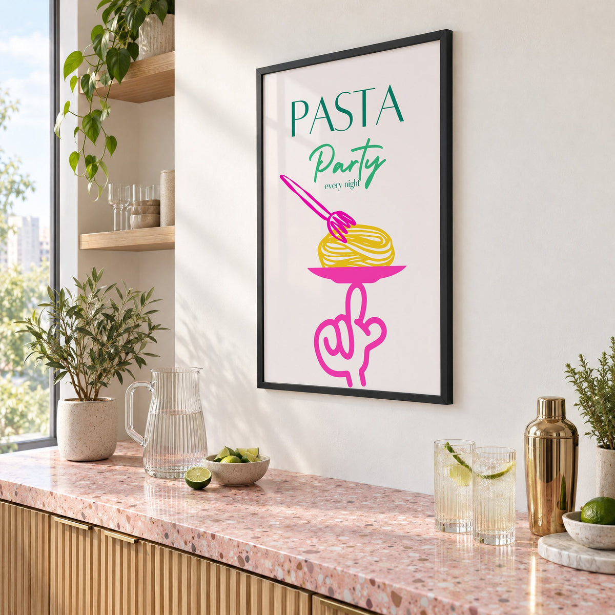 PASTA Party every night spaghetti plate print in a black frame above a pink terrazzo cocktail counter with limes, seen at an angle
