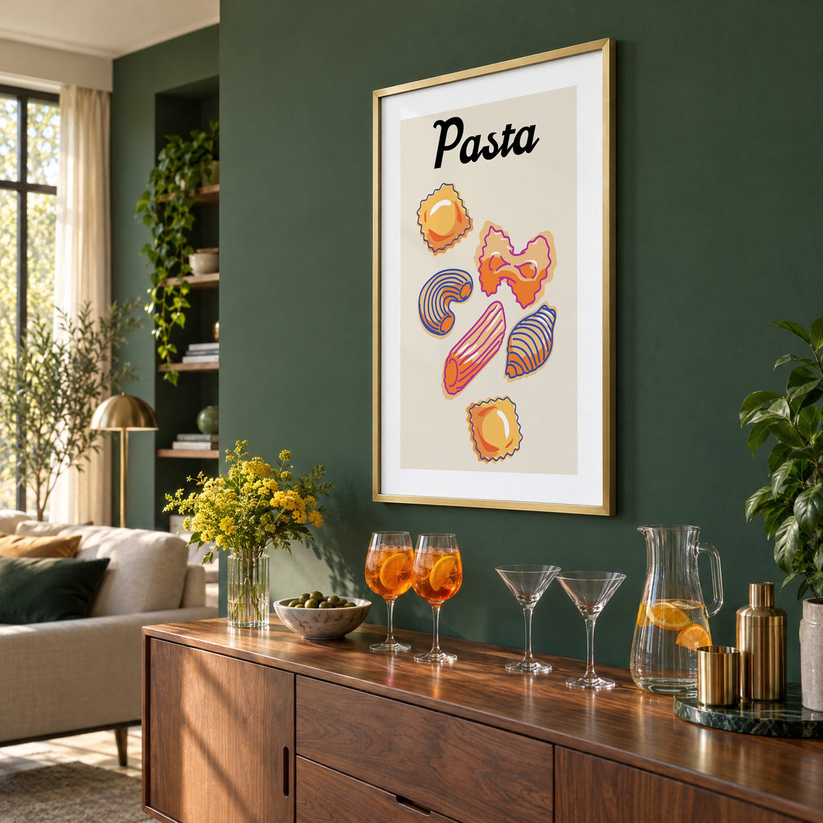 Pasta six pasta shapes offset-outline print in a brass frame on a bottle green wall above a sideboard with spritz and martini glasses, seen at an angle