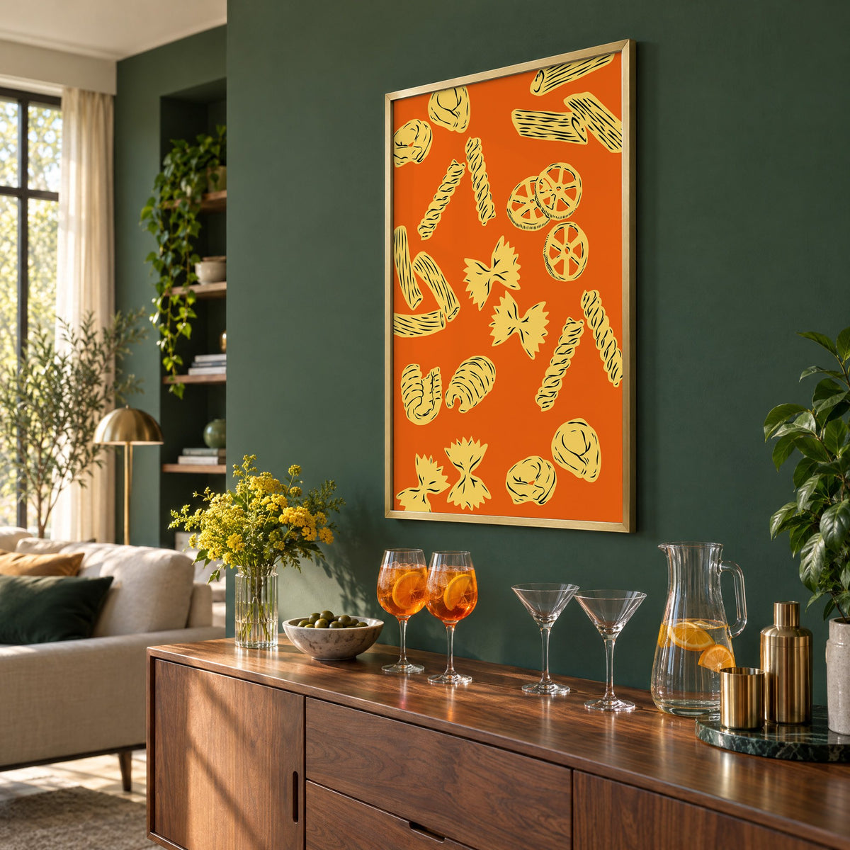 Orange pasta pattern woodcut-style print in a brass frame on a bottle green wall above a sideboard with spritz and martini glasses, seen at an angle