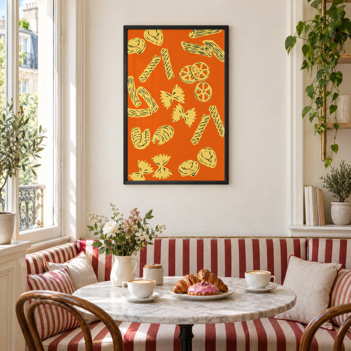Orange pasta pattern woodcut-style print in a black frame above a striped cafe breakfast nook with cappuccino and pastries