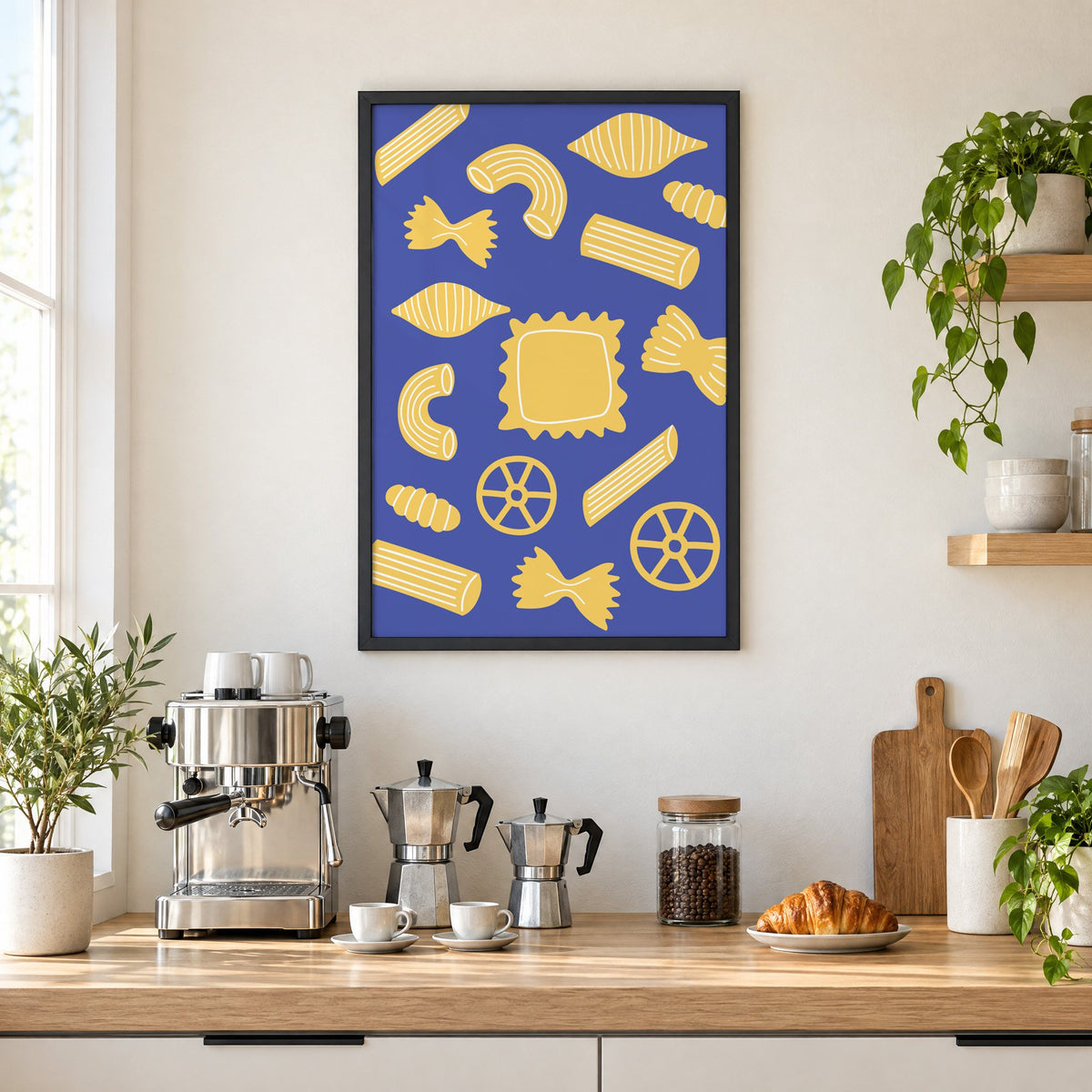 Yellow pasta shapes pattern on blue print in a black frame above a home espresso bar with moka pots and espresso cups