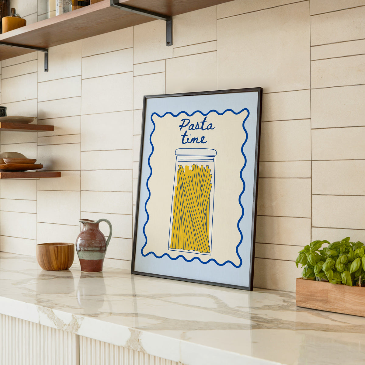 Pasta Time jar print in a black frame leaning on a marble counter in a tiled kitchen