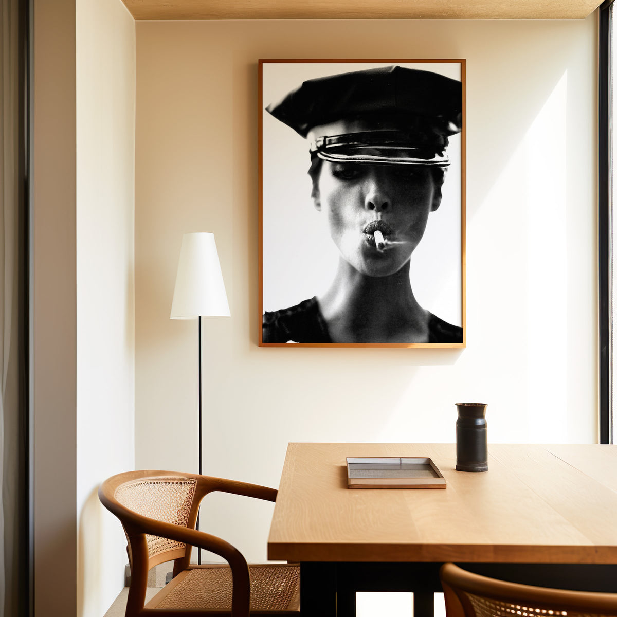 Close portrait under glossy leather cap print in an oak frame above a dining table and cane chair