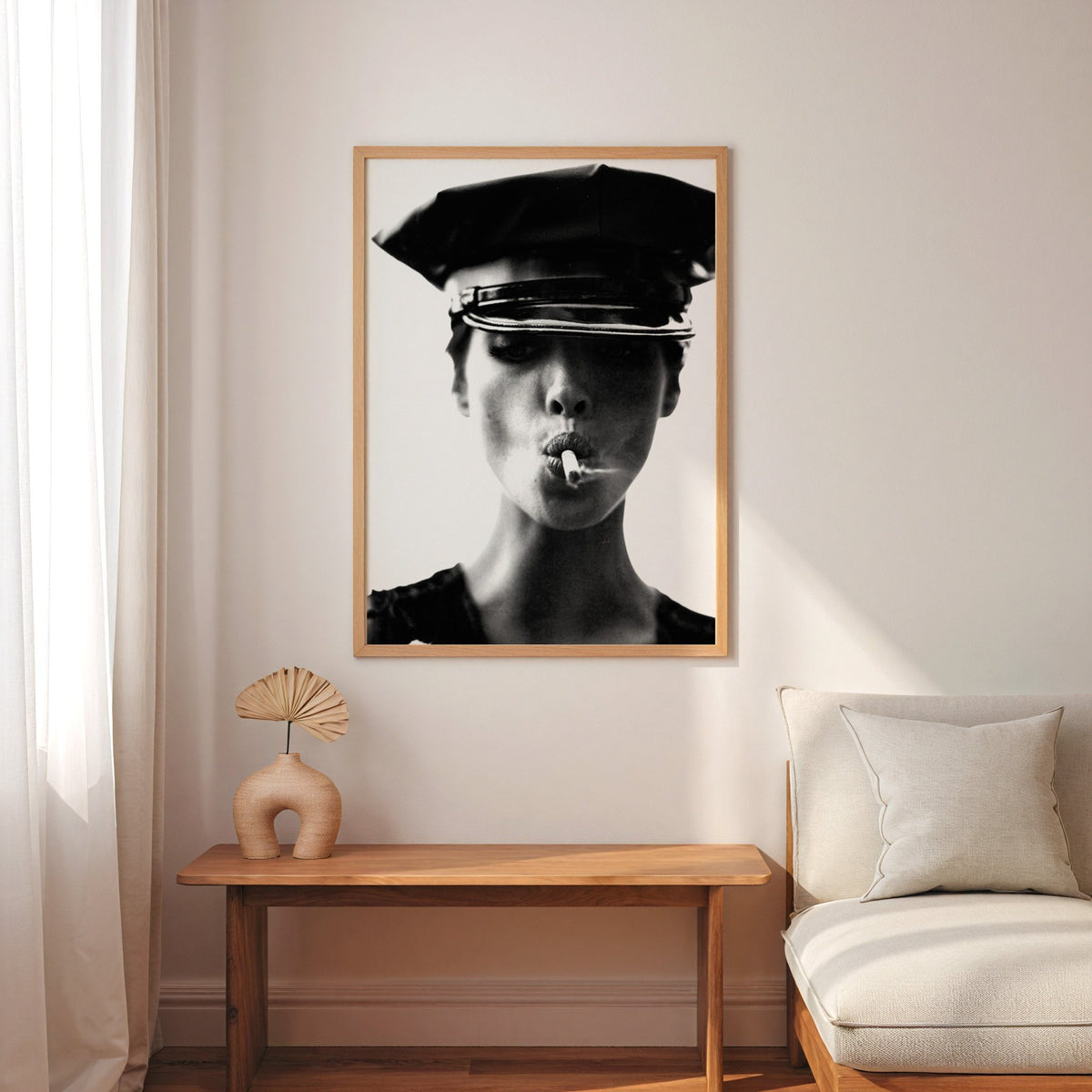 Close portrait under glossy leather cap print in an oak frame above a narrow console with an arched vase