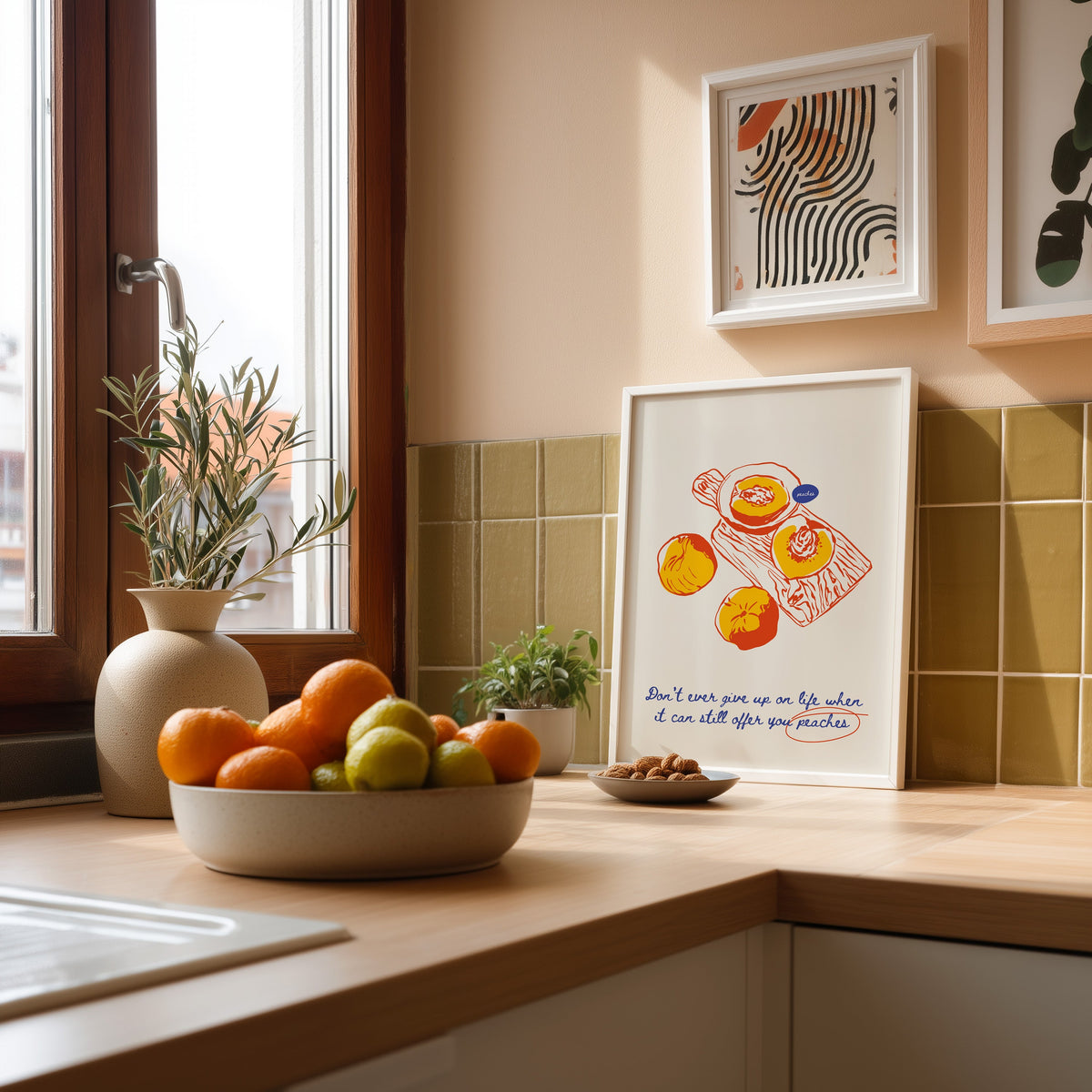 Peaches board print in a white frame against olive green kitchen tiles