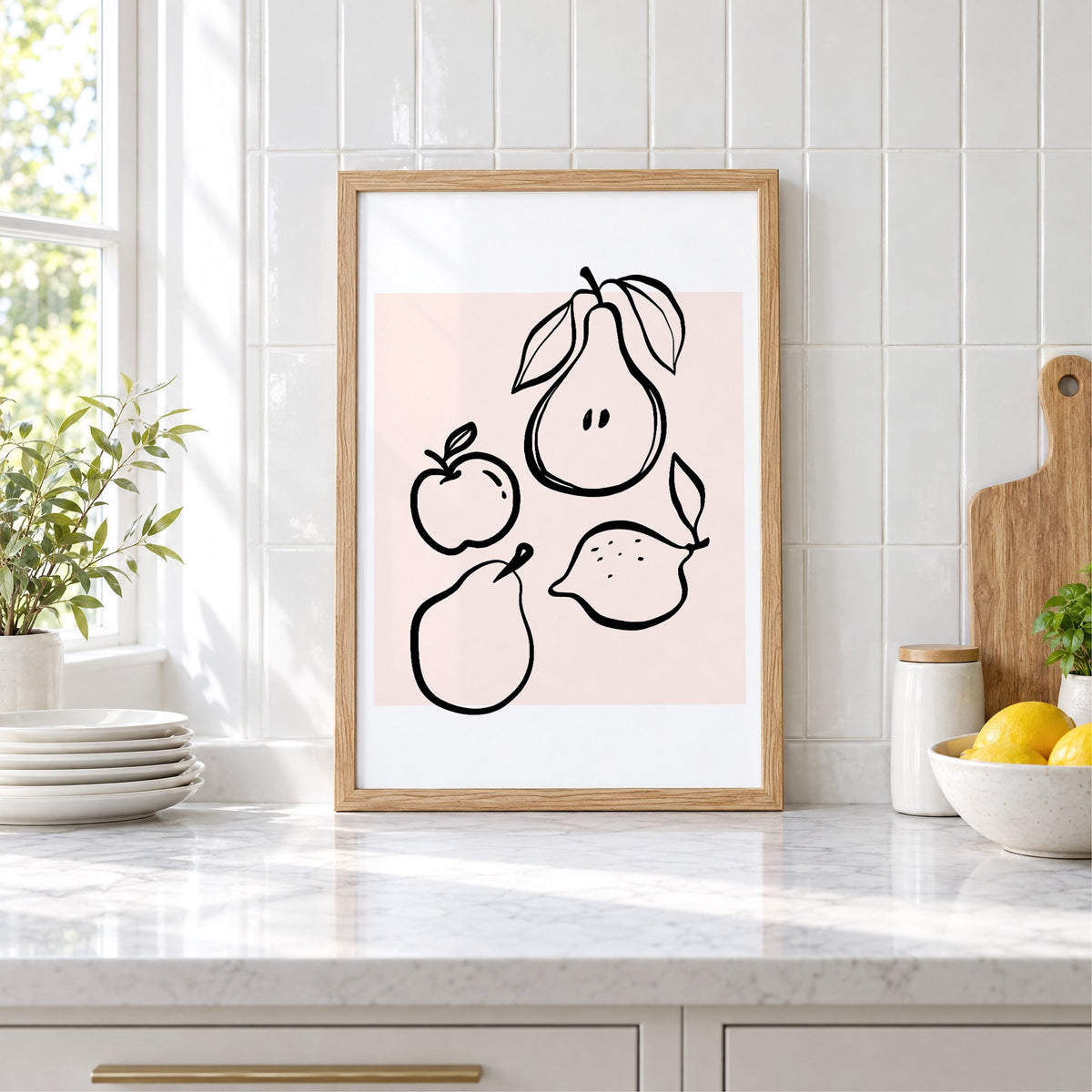Pear apple lemon black line art print in an oak frame leaning on a marble counter by white tiles and lemons