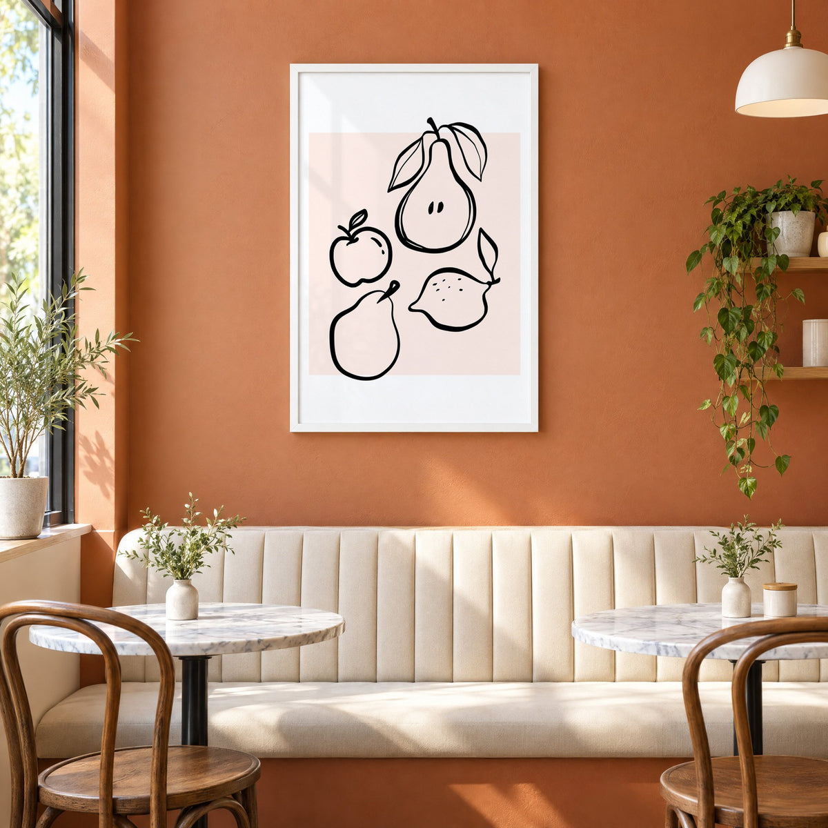 Pear apple lemon black line art print in a white frame above a cream banquette on a terracotta cafe wall