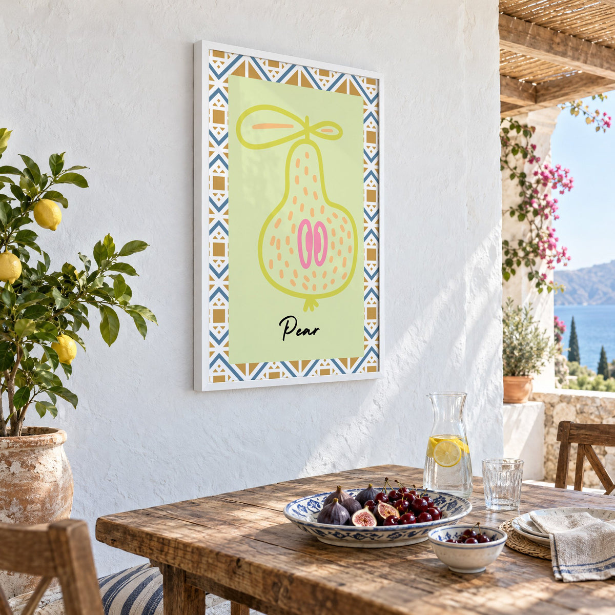 Pear lime line-art zigzag border print in a white frame on a whitewashed terrace wall above a lunch table with figs and cherries, seen at an angle