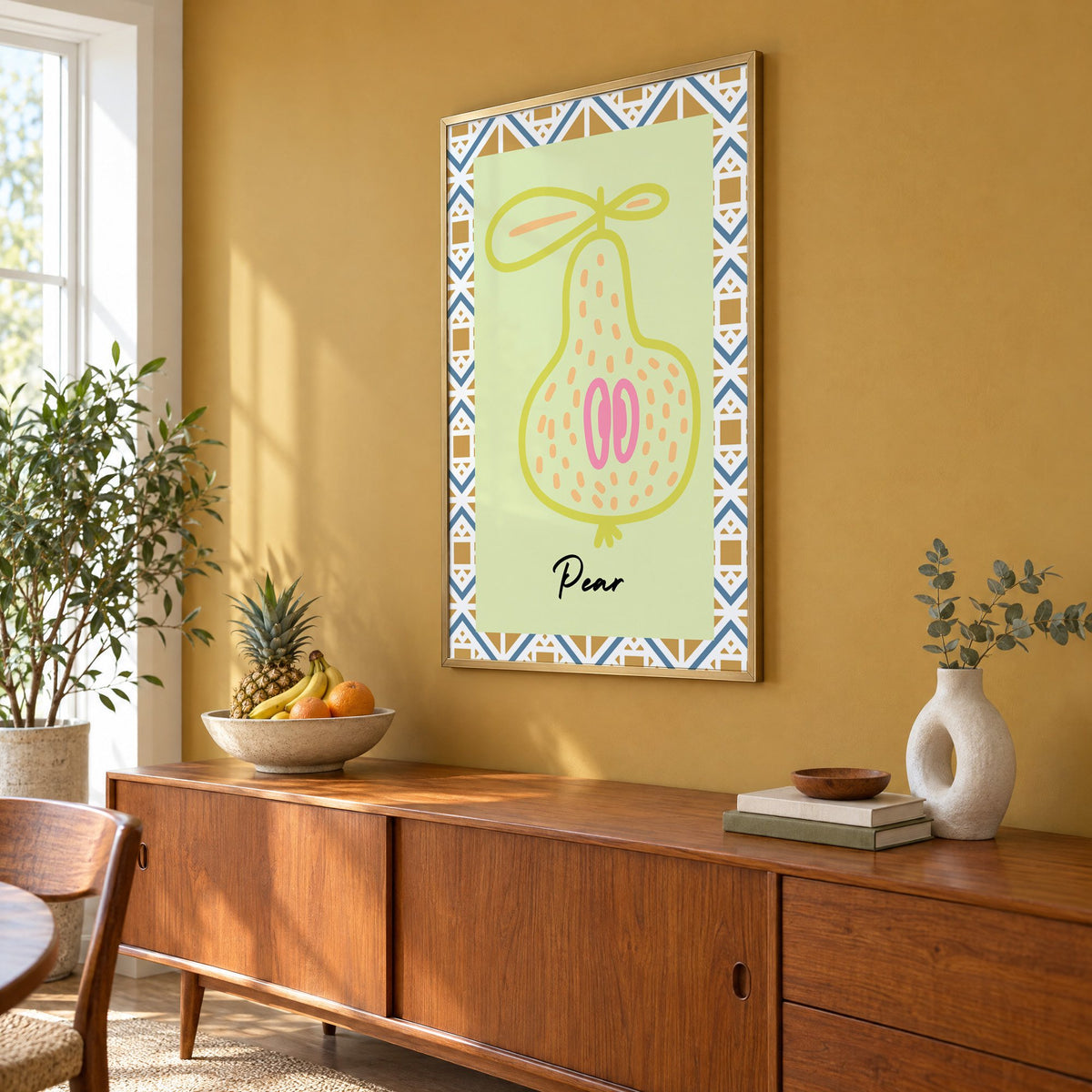 Pear lime line-art zigzag border print in a brass frame on a mustard wall above a teak sideboard with a fruit bowl, seen at an angle