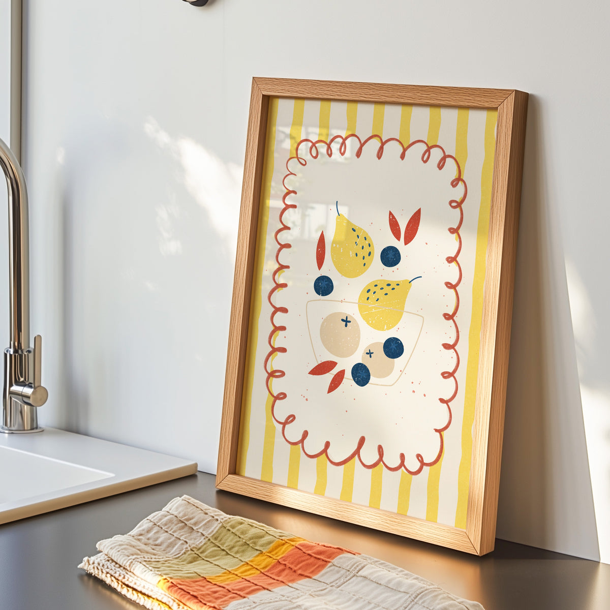 Pears and blueberries print in an oak frame by the sink with a striped tea towel