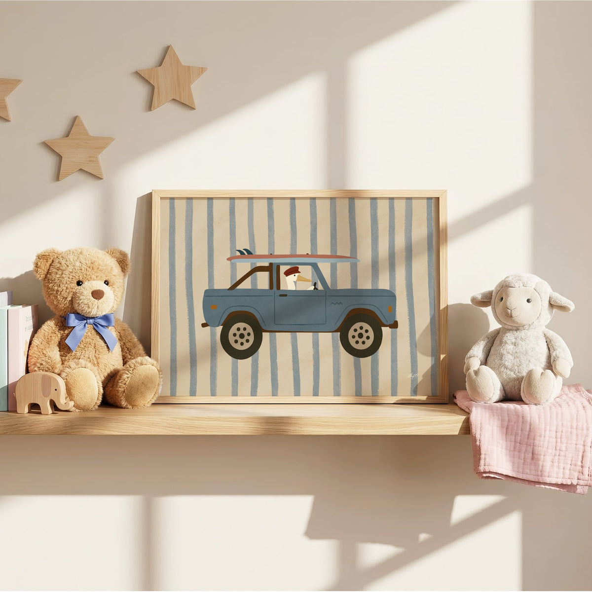 Pelican driving blue surf truck nursery print in an oak frame on a wall shelf between a teddy bear and a toy lamb