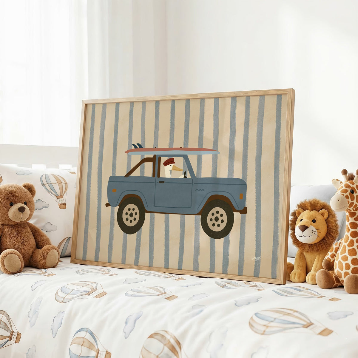 Pelican driving blue surf truck nursery print in an oak frame on a kids bed with hot air balloon bedding