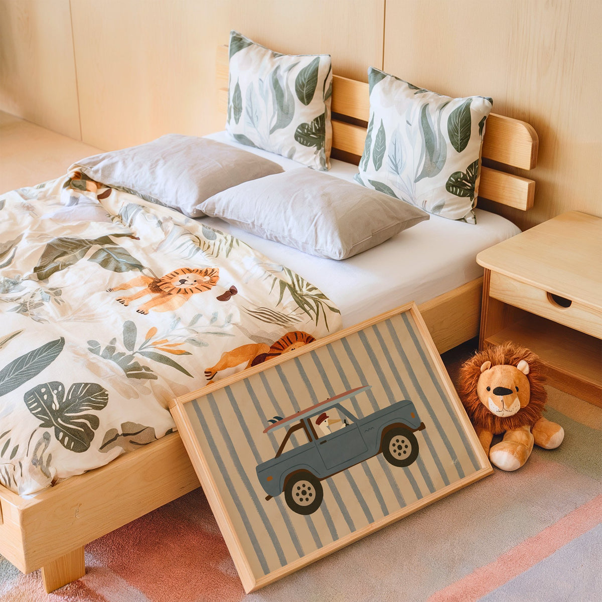 Pelican driving blue surf truck nursery print in an oak frame leaning on a kids bed by a lion plush