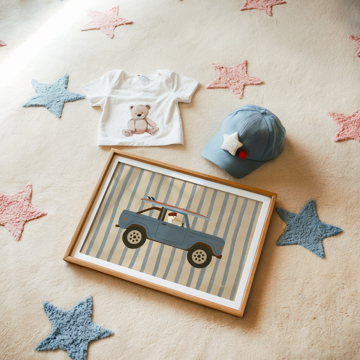 Pelican driving blue surf truck nursery print in a matted oak frame on a star rug with a baby tee