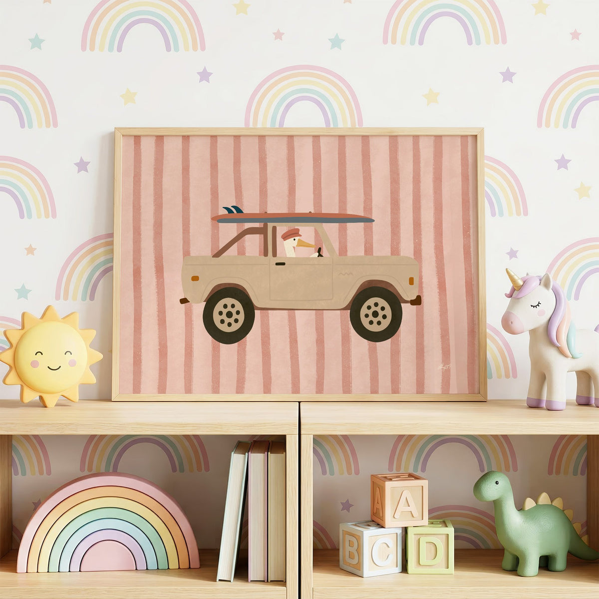 Pelican driving beige truck pink nursery print in an oak frame on a toy shelf against rainbow wallpaper
