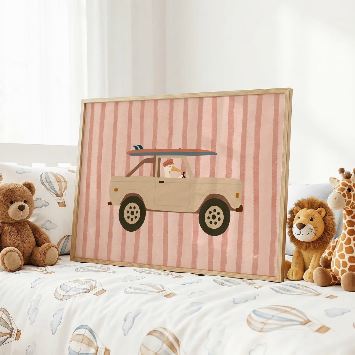 Pelican driving beige truck pink nursery print in an oak frame on a kids bed with hot air balloon bedding