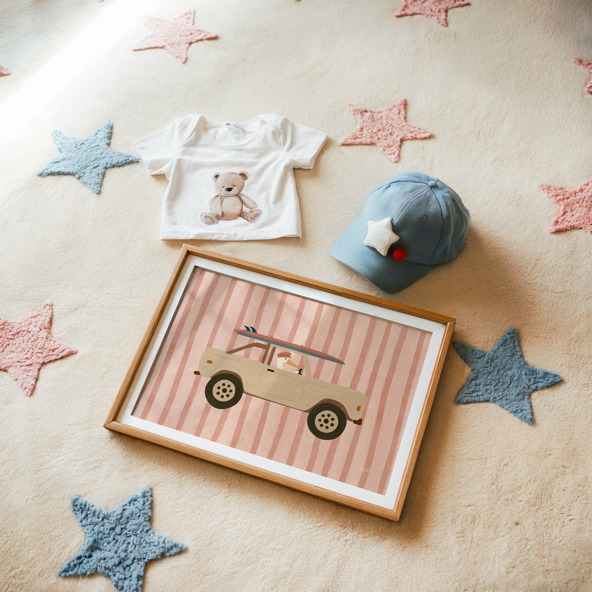 Pelican driving beige truck pink nursery print in a matted oak frame on a star rug with a baby tee