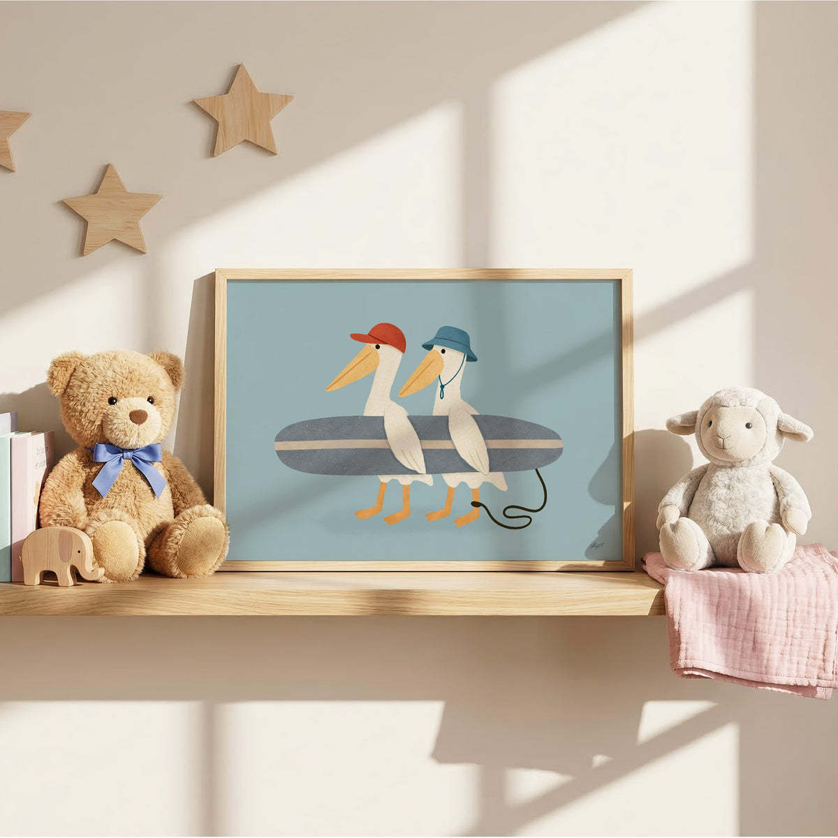 Two pelicans carrying surfboard nursery print in an oak frame on a wall shelf between a teddy bear and a toy lamb