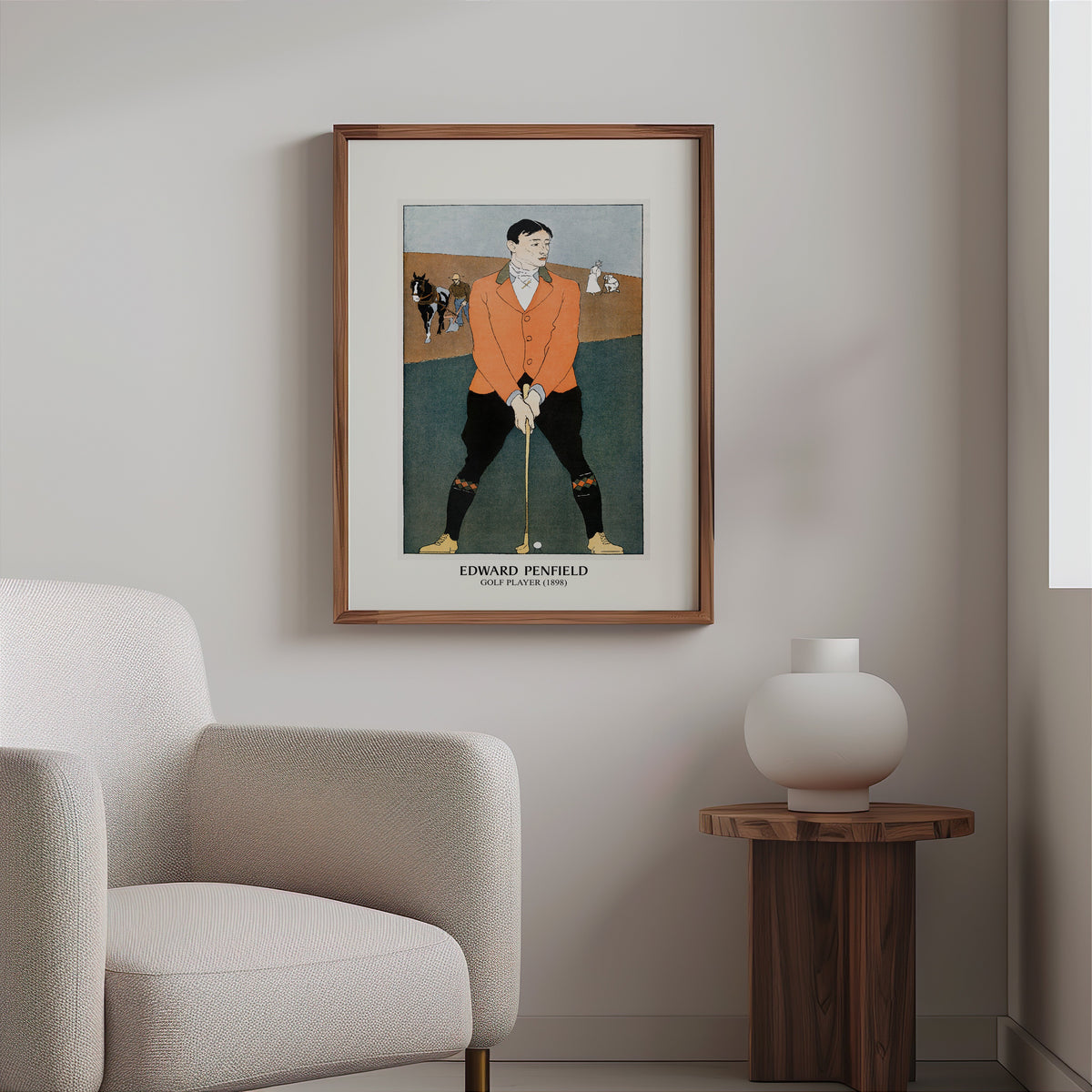 Penfield golfer poster in a slim walnut frame above a bouclé armchair