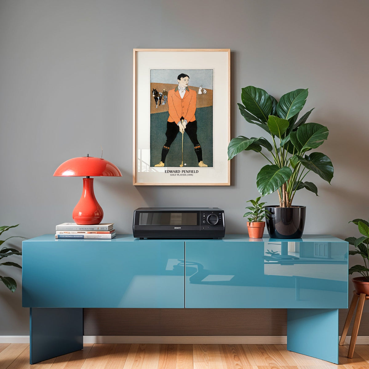 Vintage golf poster in an oak frame above a teal sideboard with a red lamp