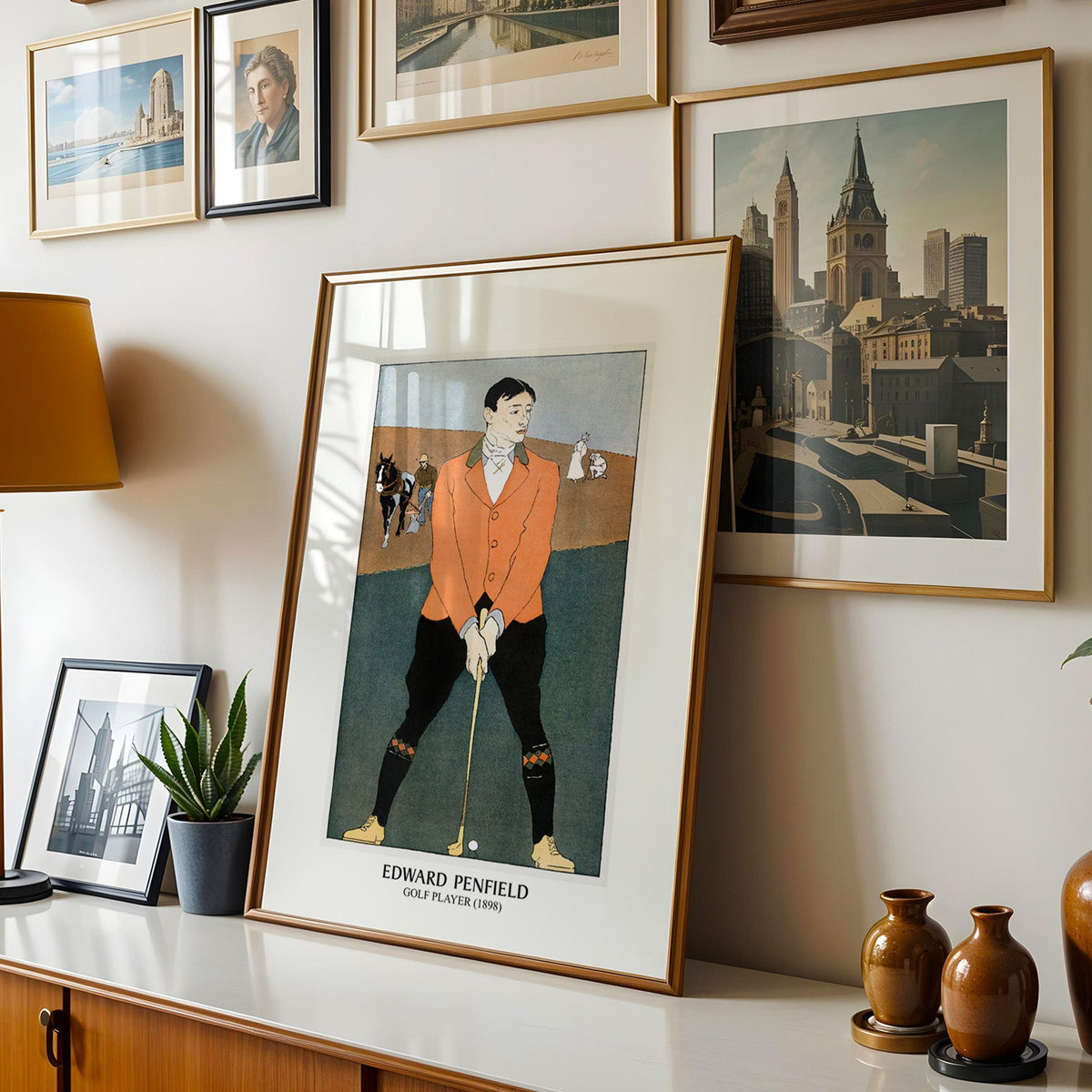 Penfield golf print shown in a gold frame leaning on a sideboard in a gallery wall
