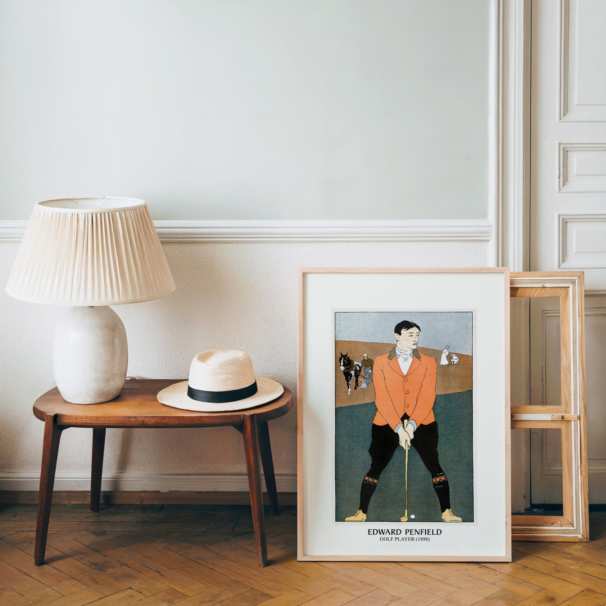 Vintage golfer poster in a light wood frame leaning by a bench and panama hat