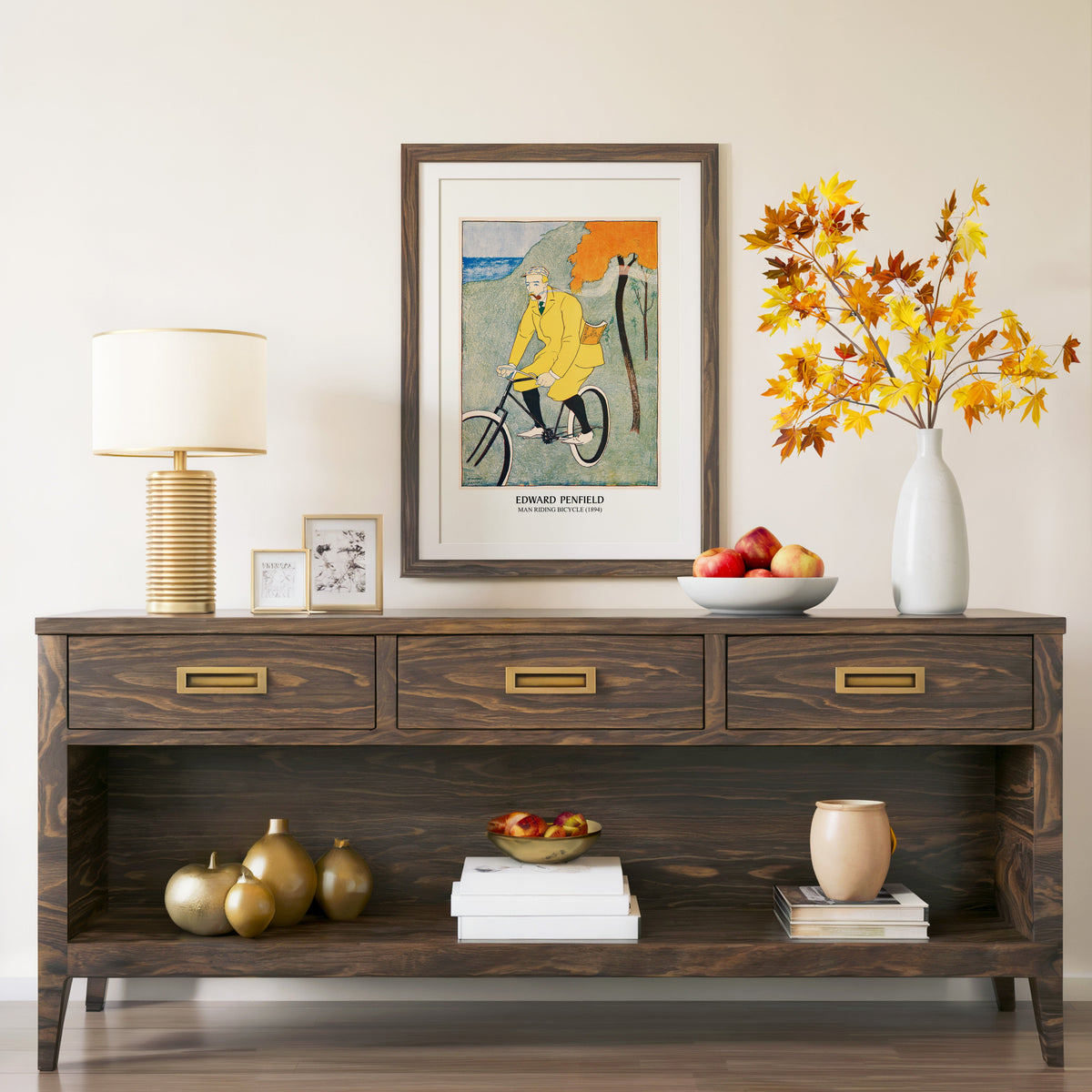 Man Riding Bicycle print in a walnut frame above a console with autumn branches