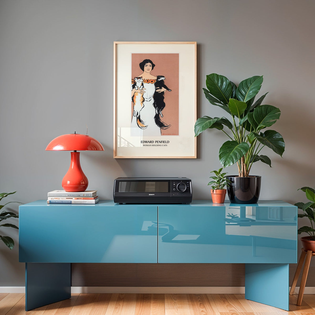 Penfield cat print in an oak frame above a teal sideboard with a red lamp