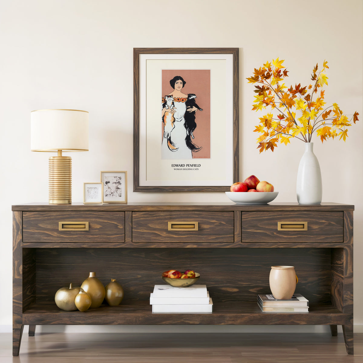 Woman Holding Cats print in a walnut frame above a console with autumn branches