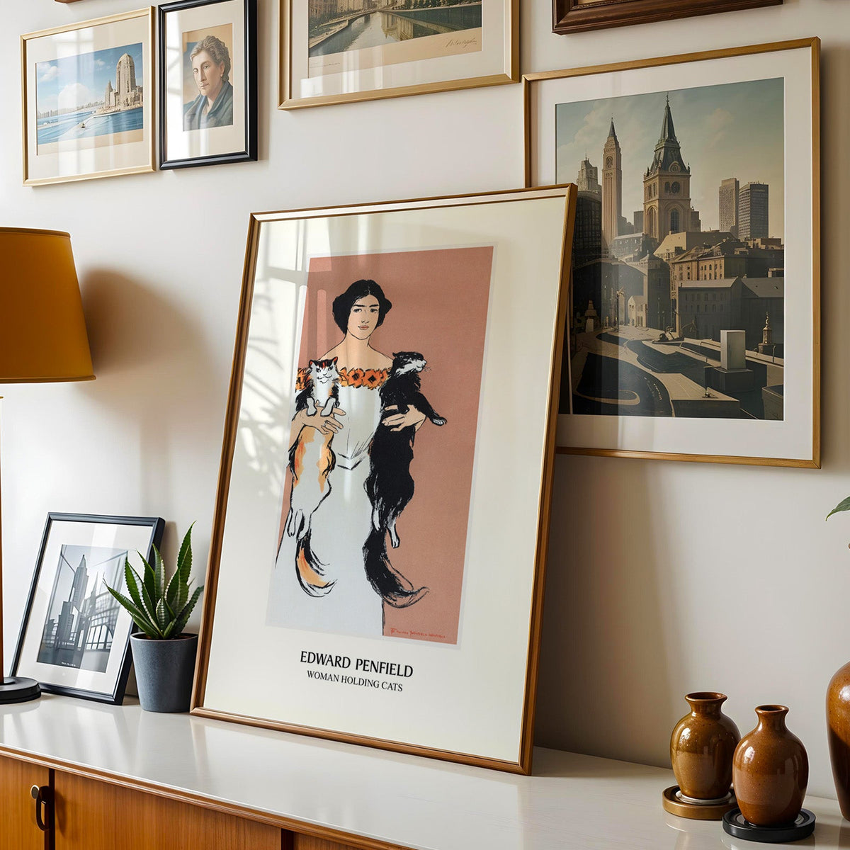 Penfield cat poster shown in a gold frame leaning on a sideboard in a gallery wall