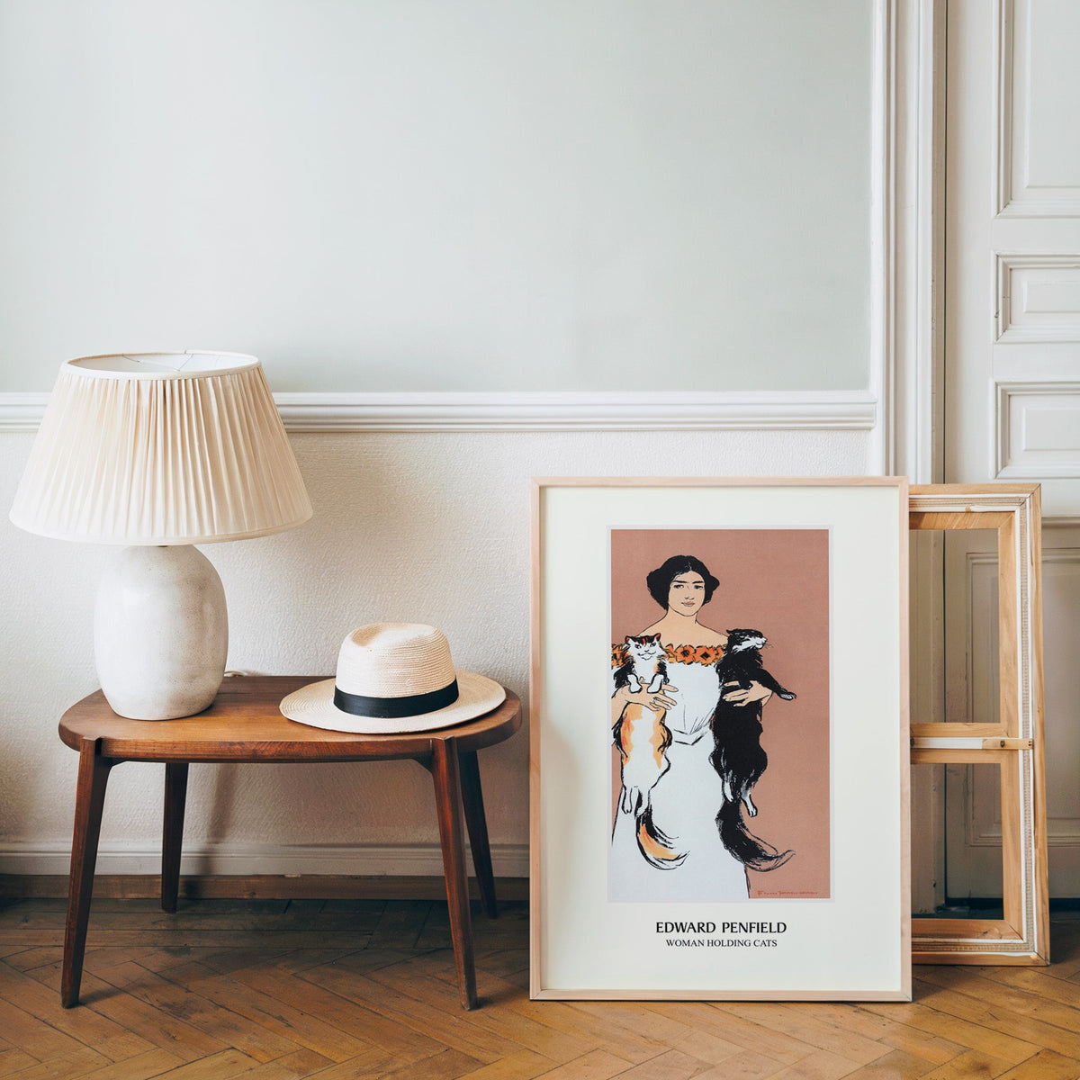 Penfield poster in a light wood frame leaning by a bench and panama hat