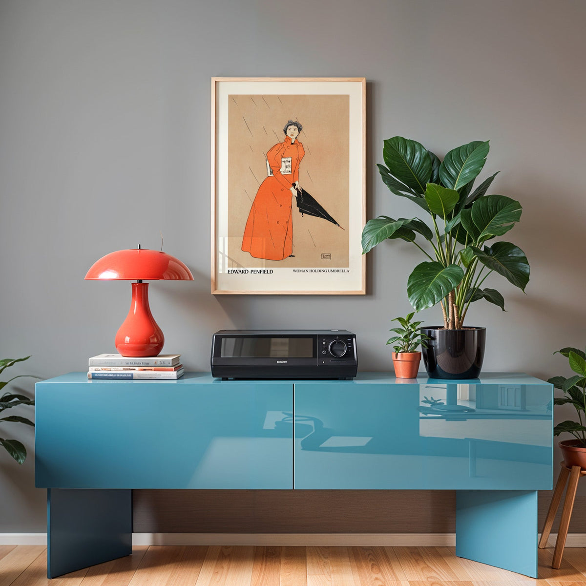 Penfield rain poster in an oak frame above a teal sideboard with a red lamp