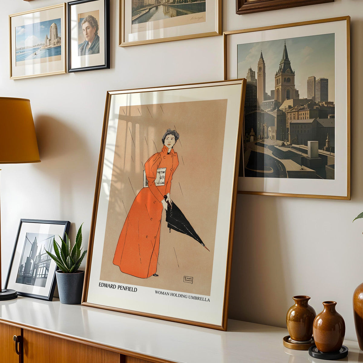 Penfield poster shown in a gold frame leaning on a sideboard in a gallery wall
