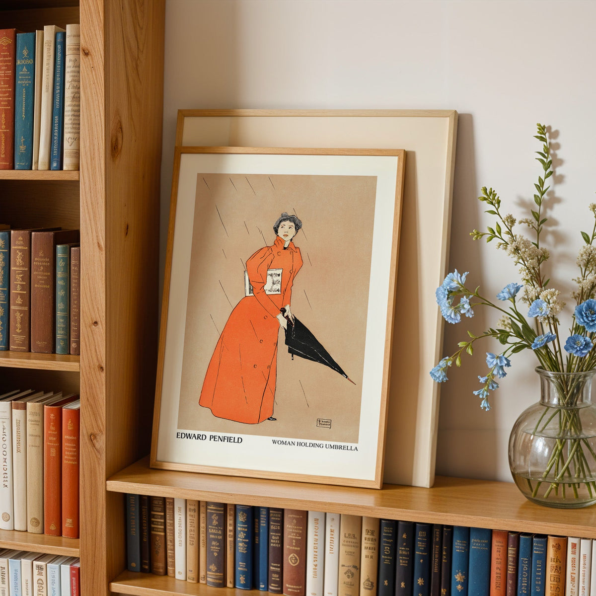 Vintage red coat print in an oak frame leaning on a bookshelf beside blue flowers