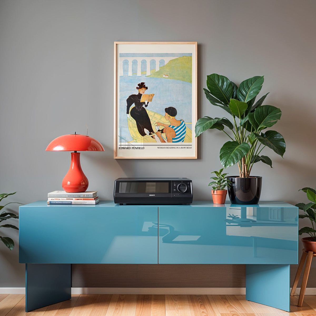 Penfield row boat print in an oak frame above a teal sideboard with a red lamp
