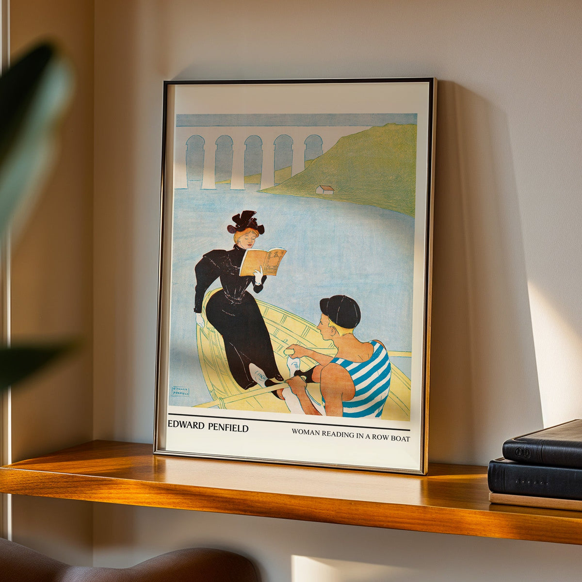 Woman Reading in a Row Boat print in a black frame on a walnut shelf