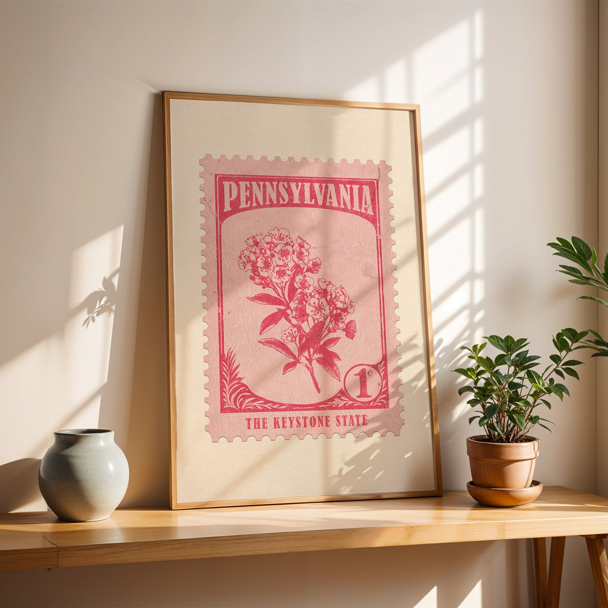 Pennsylvania Mountain Laurel stamp print in a light oak frame leaning on a wooden table beside a stoneware vase