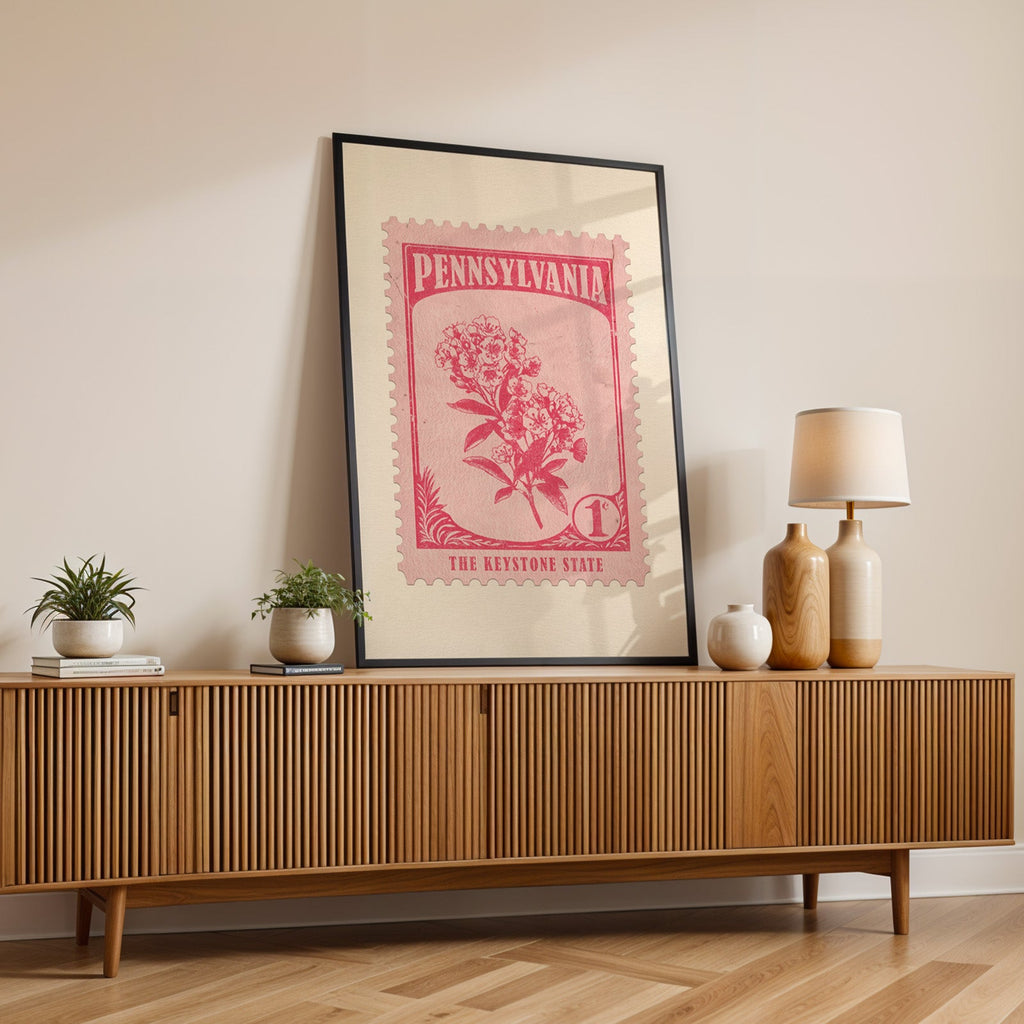 Pennsylvania state flower print in a black frame leaning on a fluted wood credenza with vases and a lamp