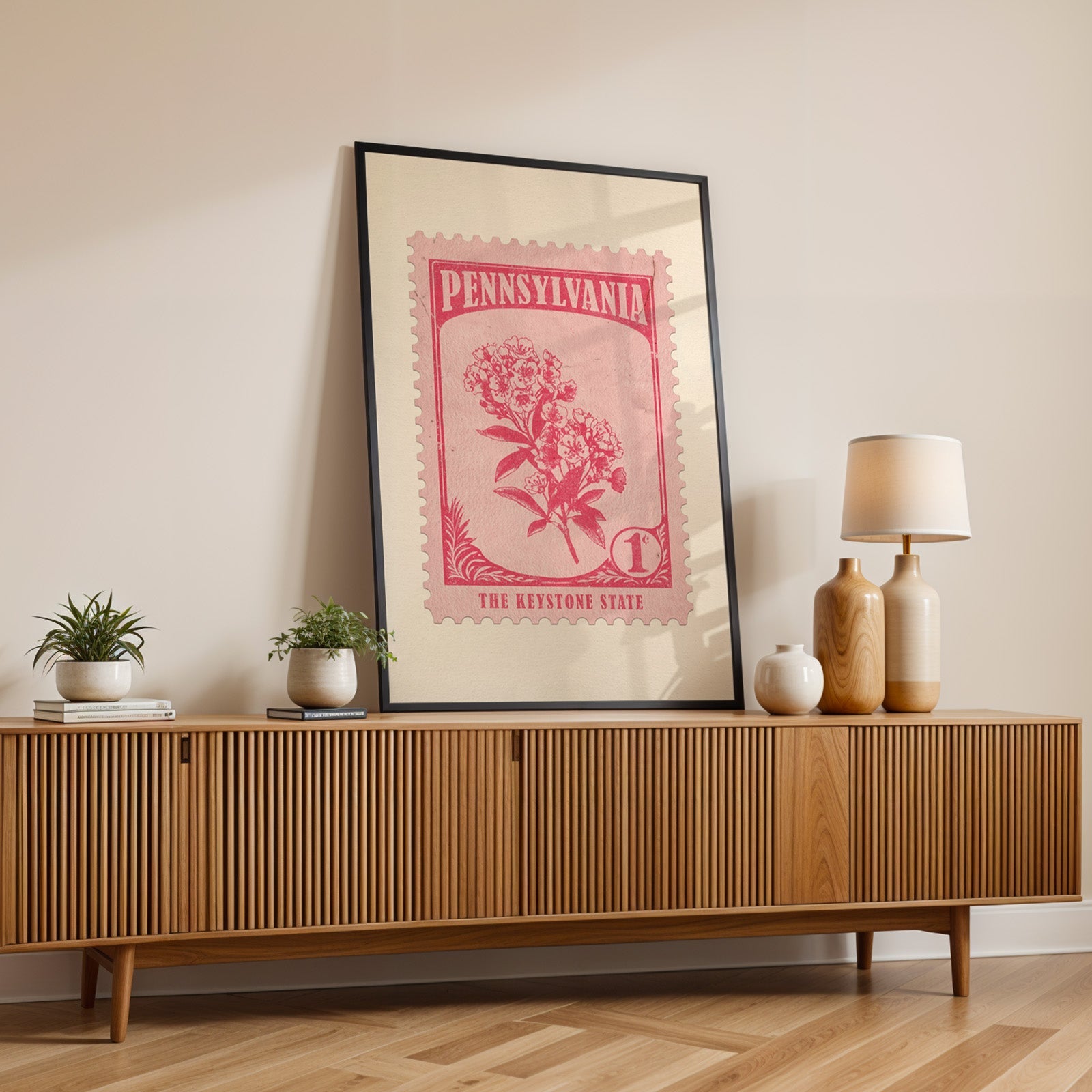 Pennsylvania state flower print in a black frame leaning on a fluted wood credenza with vases and a lamp