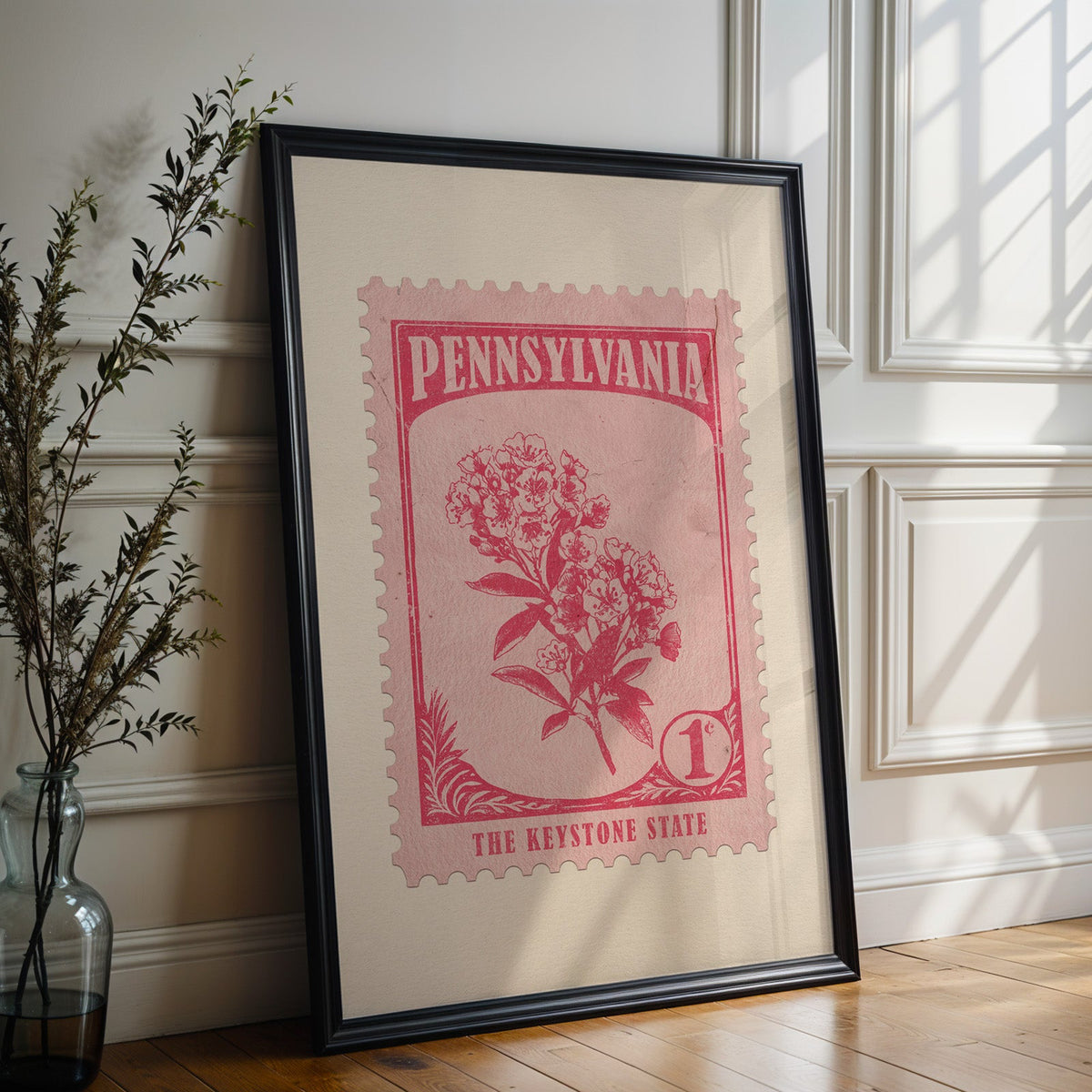 Pennsylvania state flower print in a black frame leaning against a white panelled wall beside olive branches