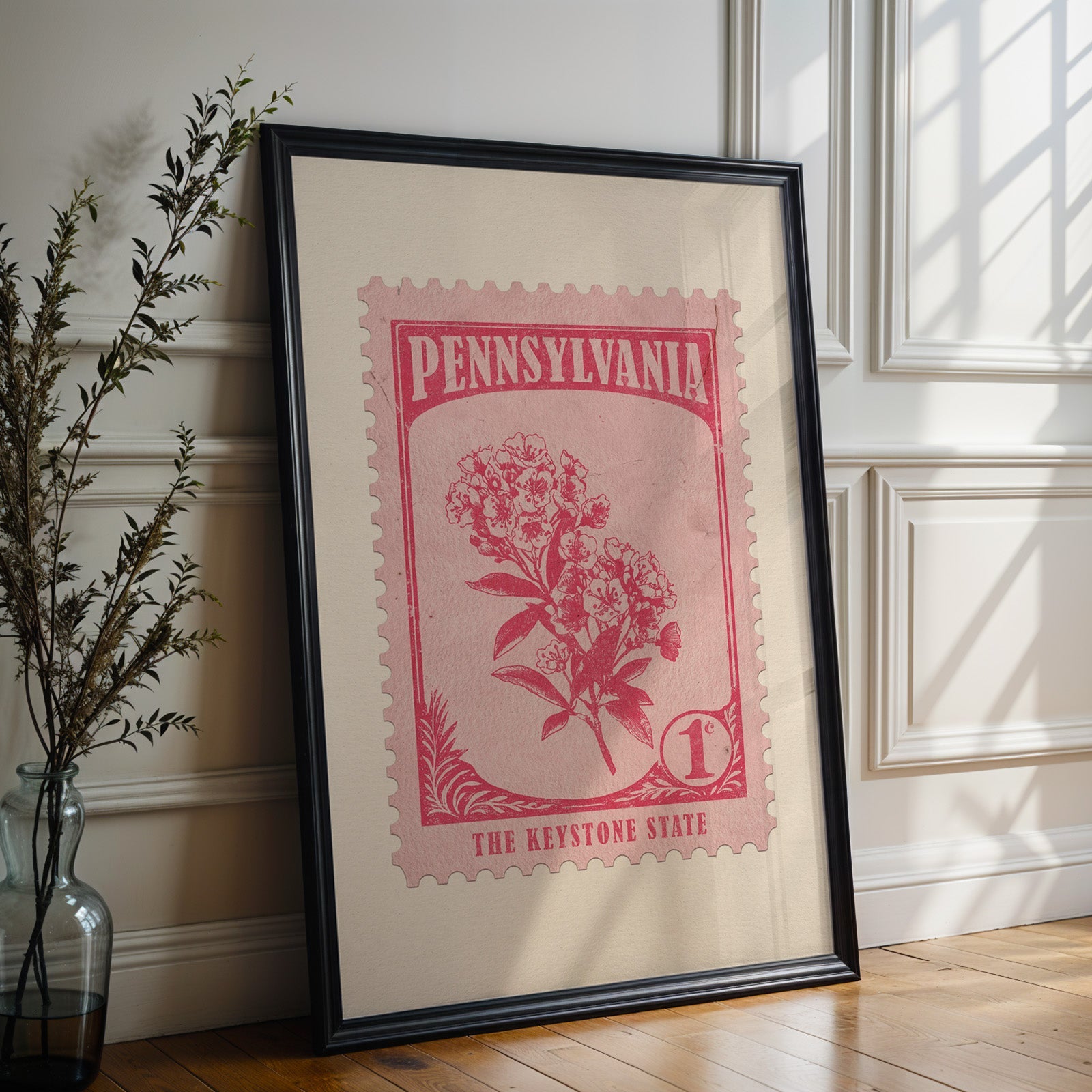 Pennsylvania state flower print in a black frame leaning against a white panelled wall beside olive branches