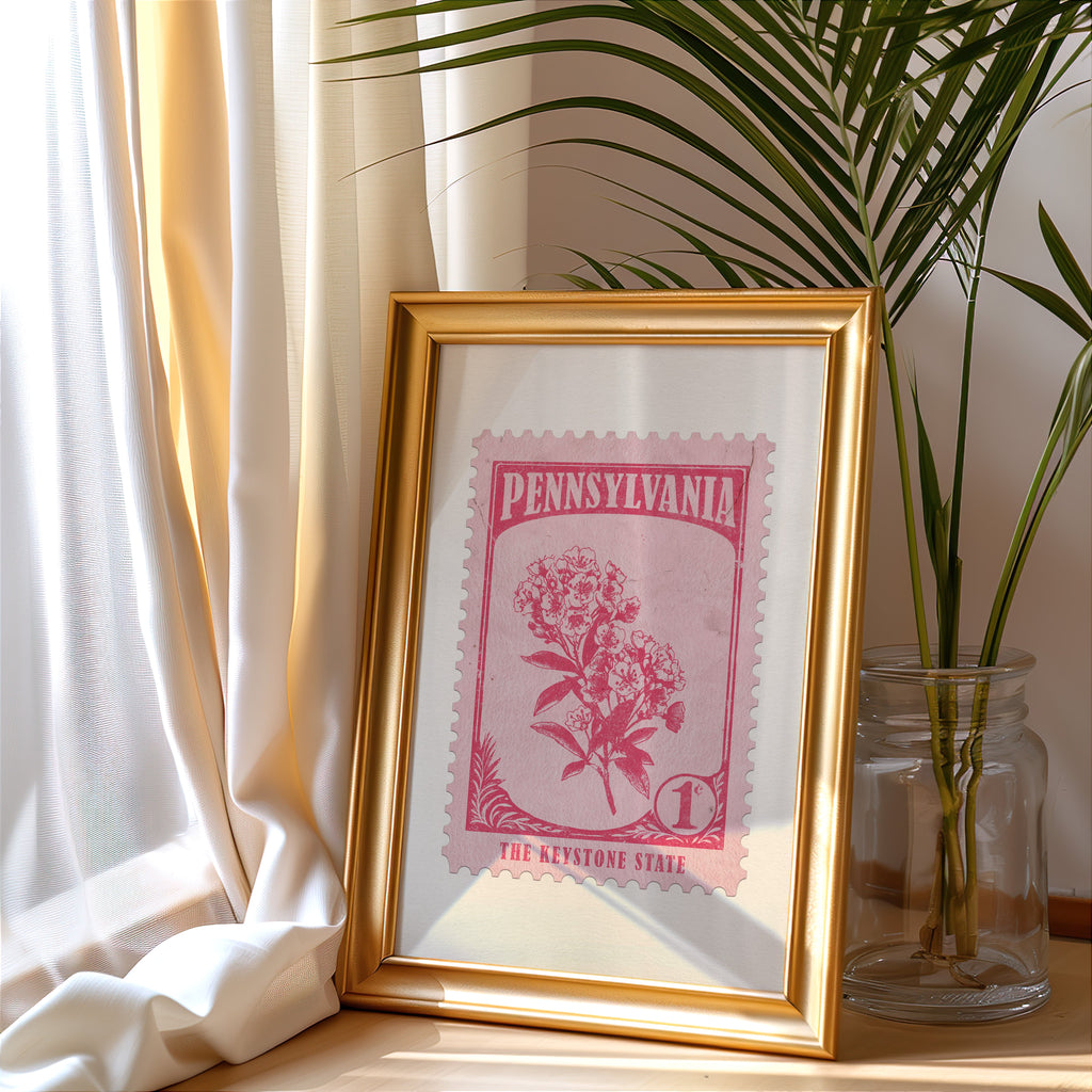 Pennsylvania stamp print in a gold frame leaning by a cream curtain with a palm in a glass jar