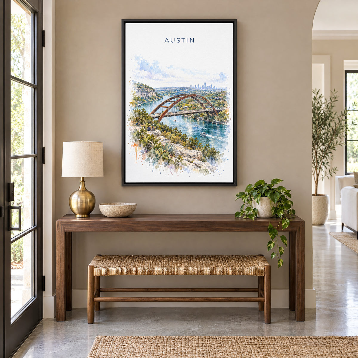 Pennybacker Bridge Austin watercolor print as a black floater canvas above a walnut console and woven bench in an entryway