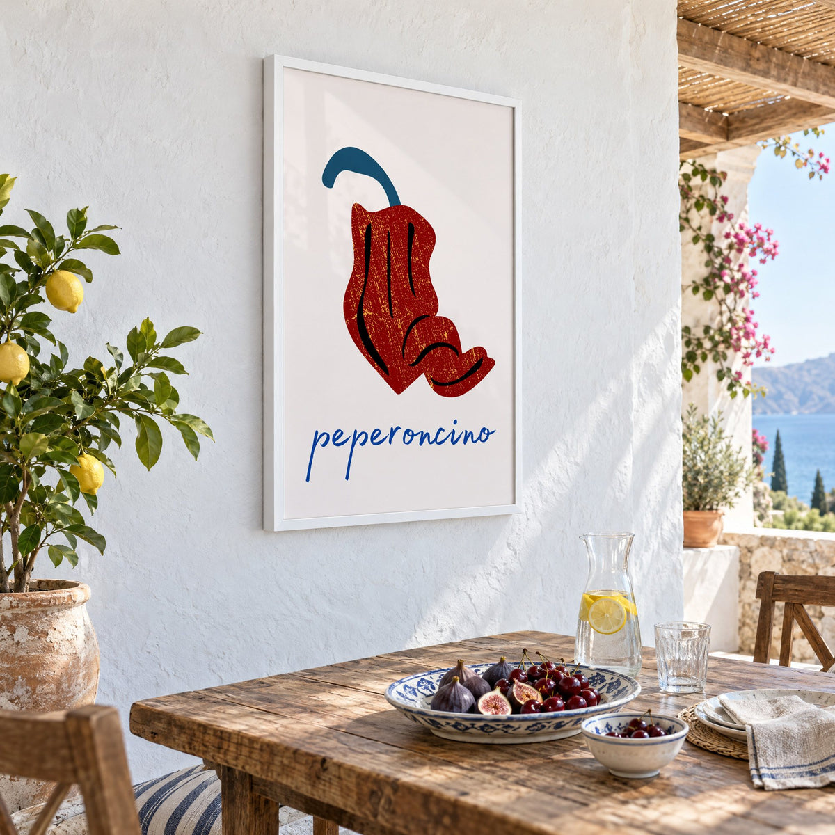 peperoncino red chili grunge print in a white frame on a whitewashed terrace wall above a lunch table with figs and cherries, seen at an angle