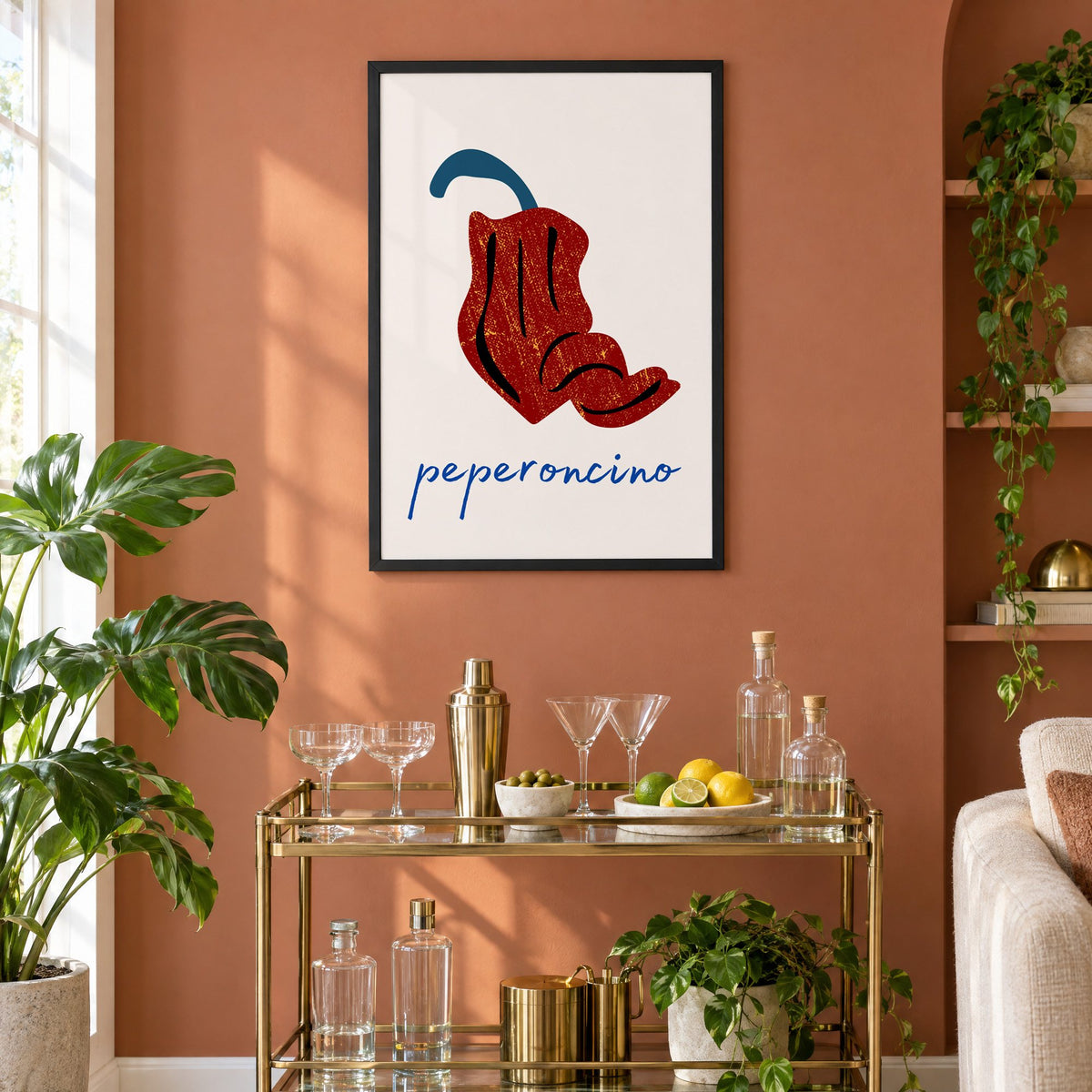 peperoncino red chili grunge print in a black frame on a terracotta wall above a brass bar cart with coupes and citrus